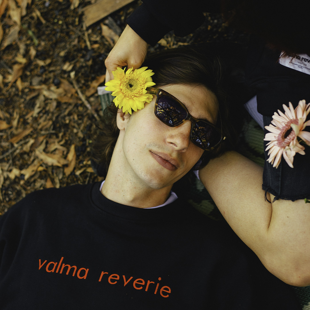 Modelo acostado en el pasto vistiendo ropa de la marca Valma Reverie